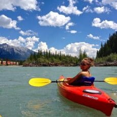 Registered veterinarian technician kayaking with a bright blue sky behind her